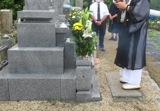 お墓の前で読経する僧侶