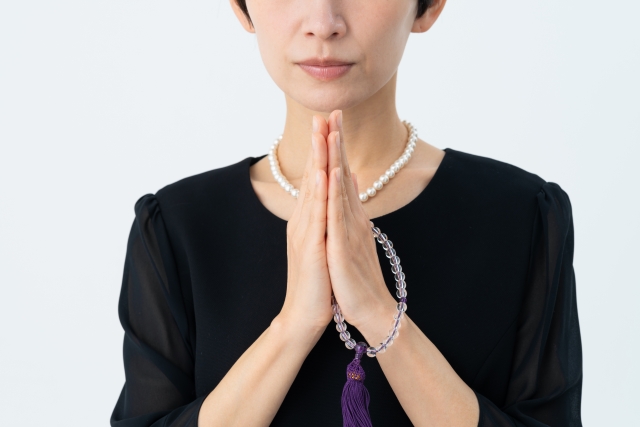 合掌する喪服の女性
