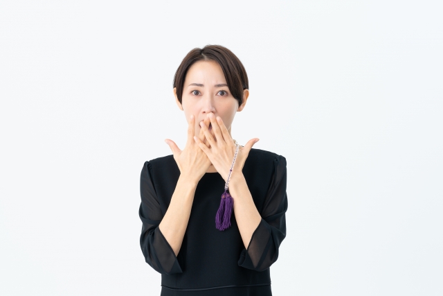 驚く喪服の女性